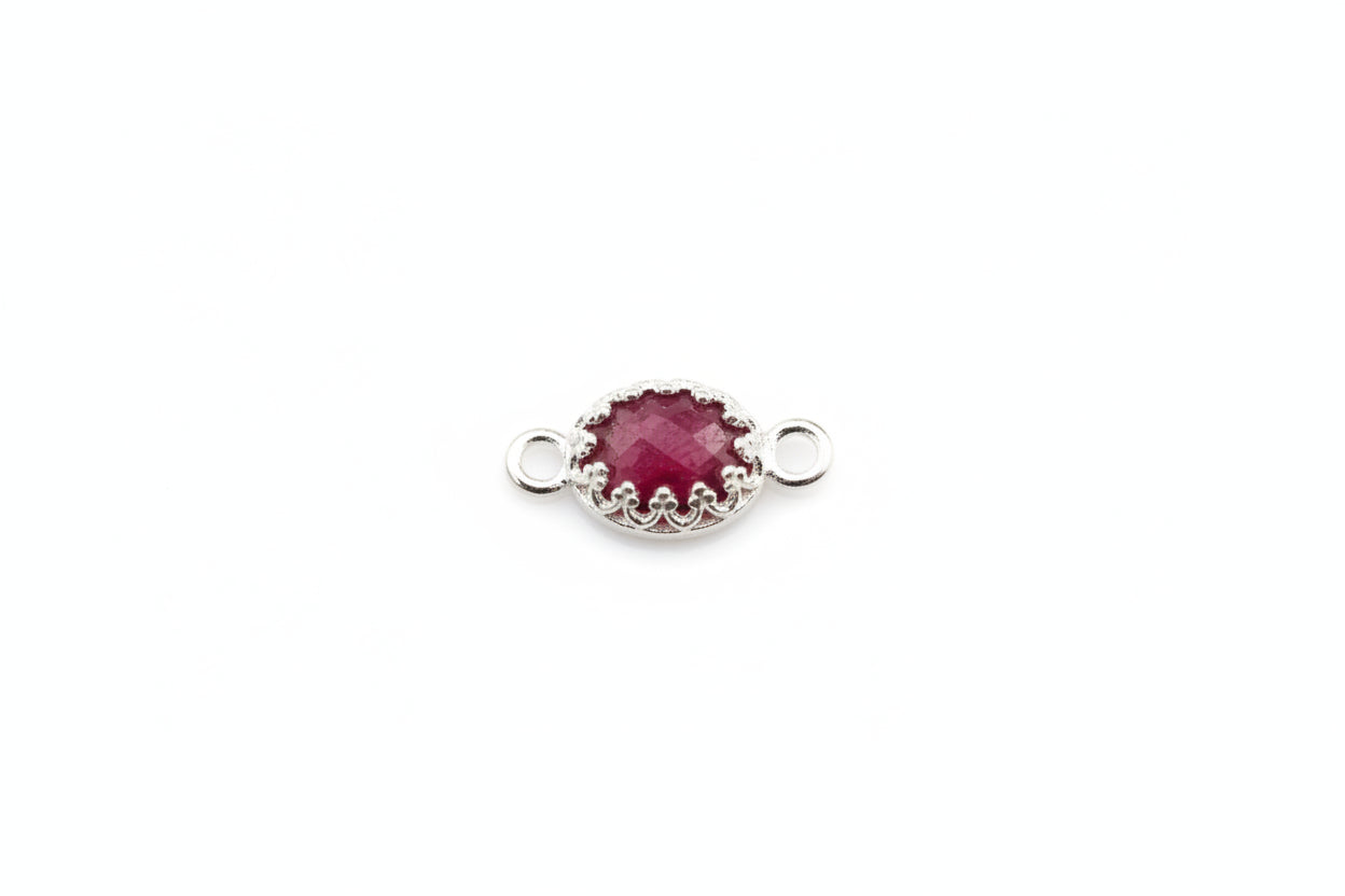 Silver connector with a red gemstone on a marble background