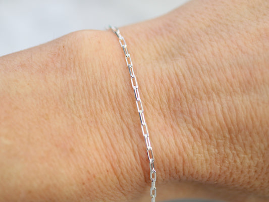 Silver chain bracelet on a wrist against a neutral background