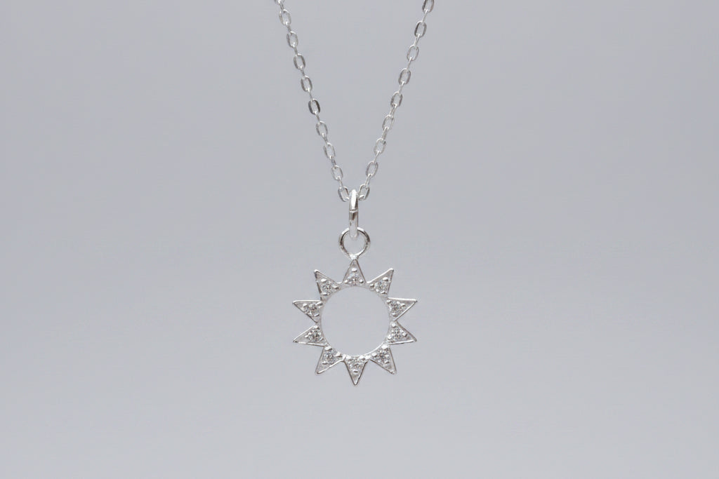 Silver star-shaped pendant necklace on a marble surface with flowers in the background