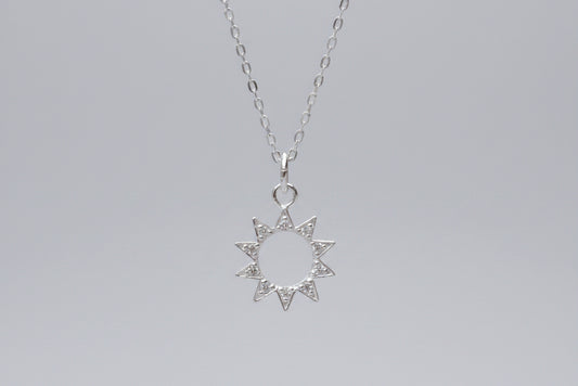 Silver star-shaped pendant necklace on a marble surface with flowers in the background