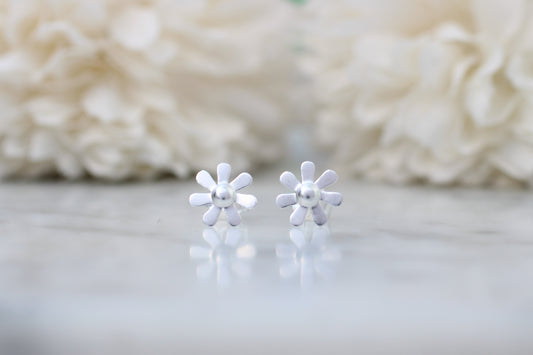 silver flower-shaped earrings on a light background