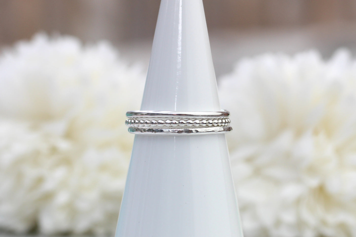 Silver ring on a white cone with a blurred white floral background