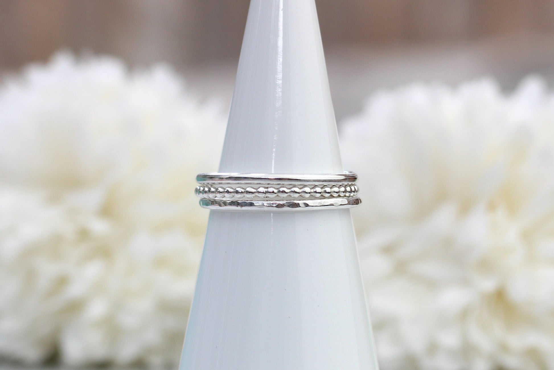 Silver ring on a white cone with a blurred white floral background