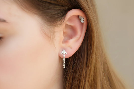 Close-up of a person wearing silver earrings with a blurred background