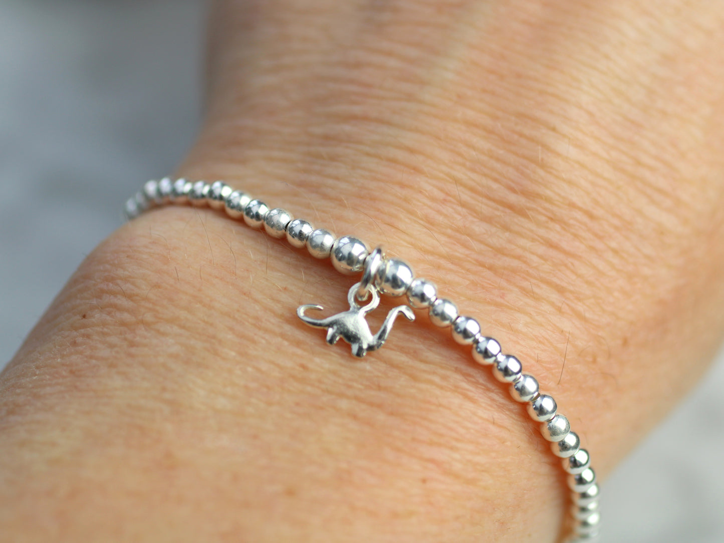 dinosaur charm bracelet being worn on the wrist