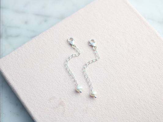Pearl earrings on a pink jewelry box with a light marble background
