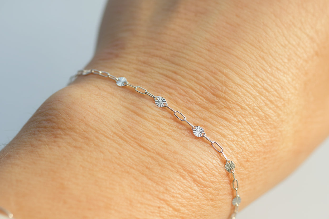 sunburst and paperclip bracelet on a wrist