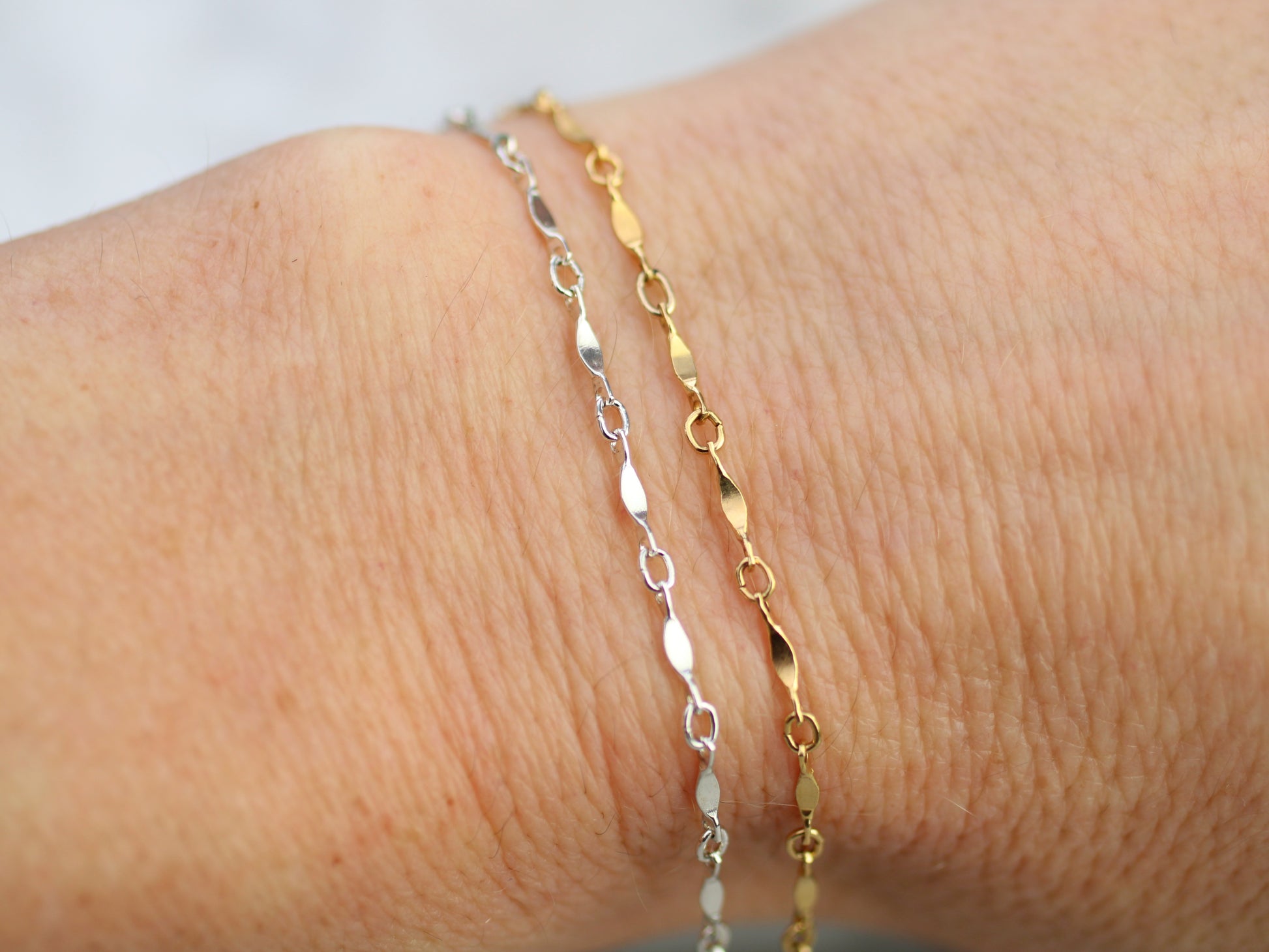 Two gold and silver bracelets on a wrist against a white background