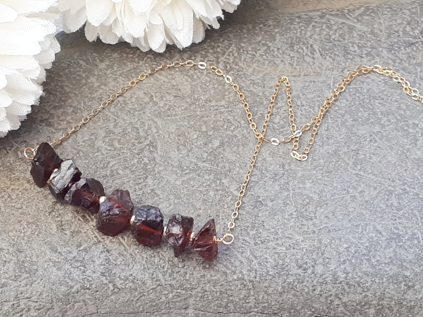 Raw garnet gemstone necklace in gold.