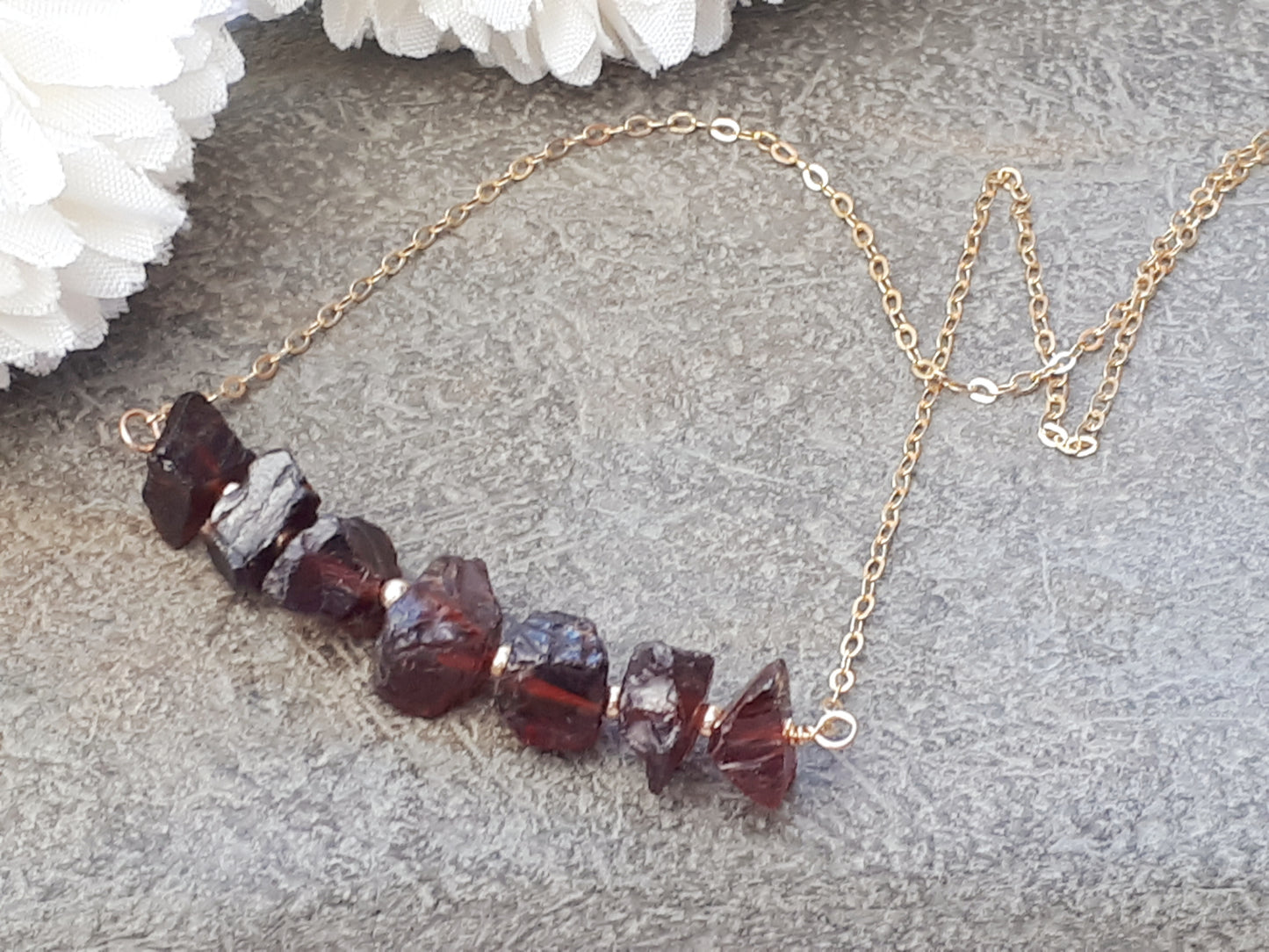 Raw garnet gemstone necklace in gold.